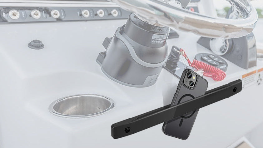 A black smartphone mounting bar with a magnetic phone holder, shown attached to a boat console with a steering wheel and dashboard controls in the background.